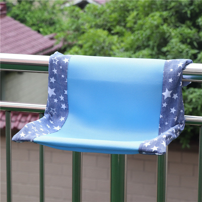super portable cat nest on a balcony railing with blue and star-patterned fabric.