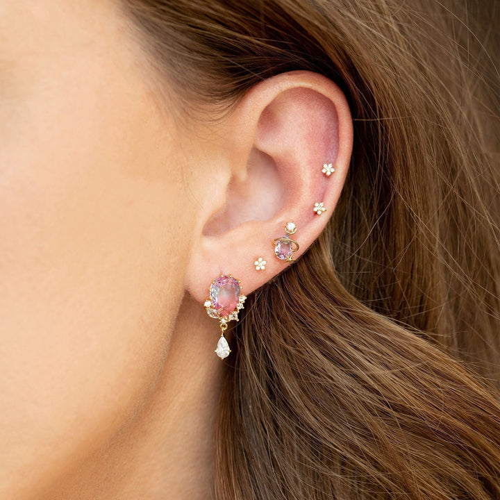 Close-up of ear featuring gold zircon flower ear studs and decorative ear jewelry in a stylish arrangement.