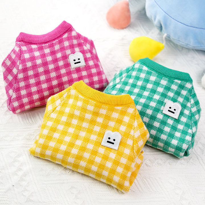 Warm pet sweaters in pink, green, and yellow colors with smiley face designs, perfect for colder seasons.